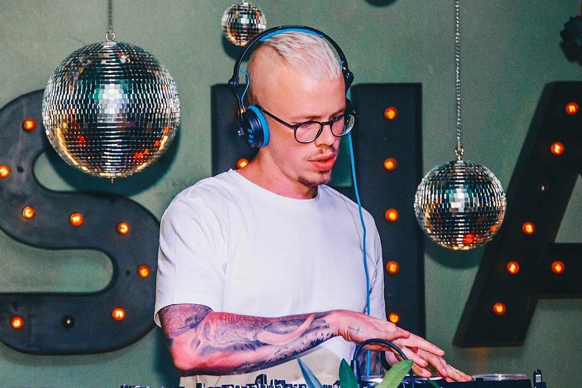 DJ Aidin Caye performing under a disco ball